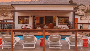 Uma casa moderna com piscina e espreguiçadeiras.