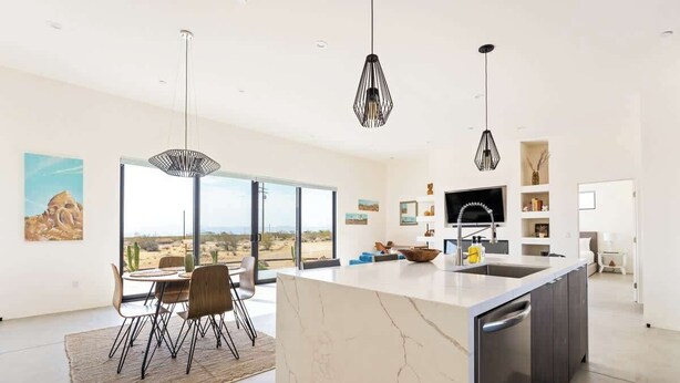 Una cocina moderna con una isla grande, luces colgantes y vistas al desierto.