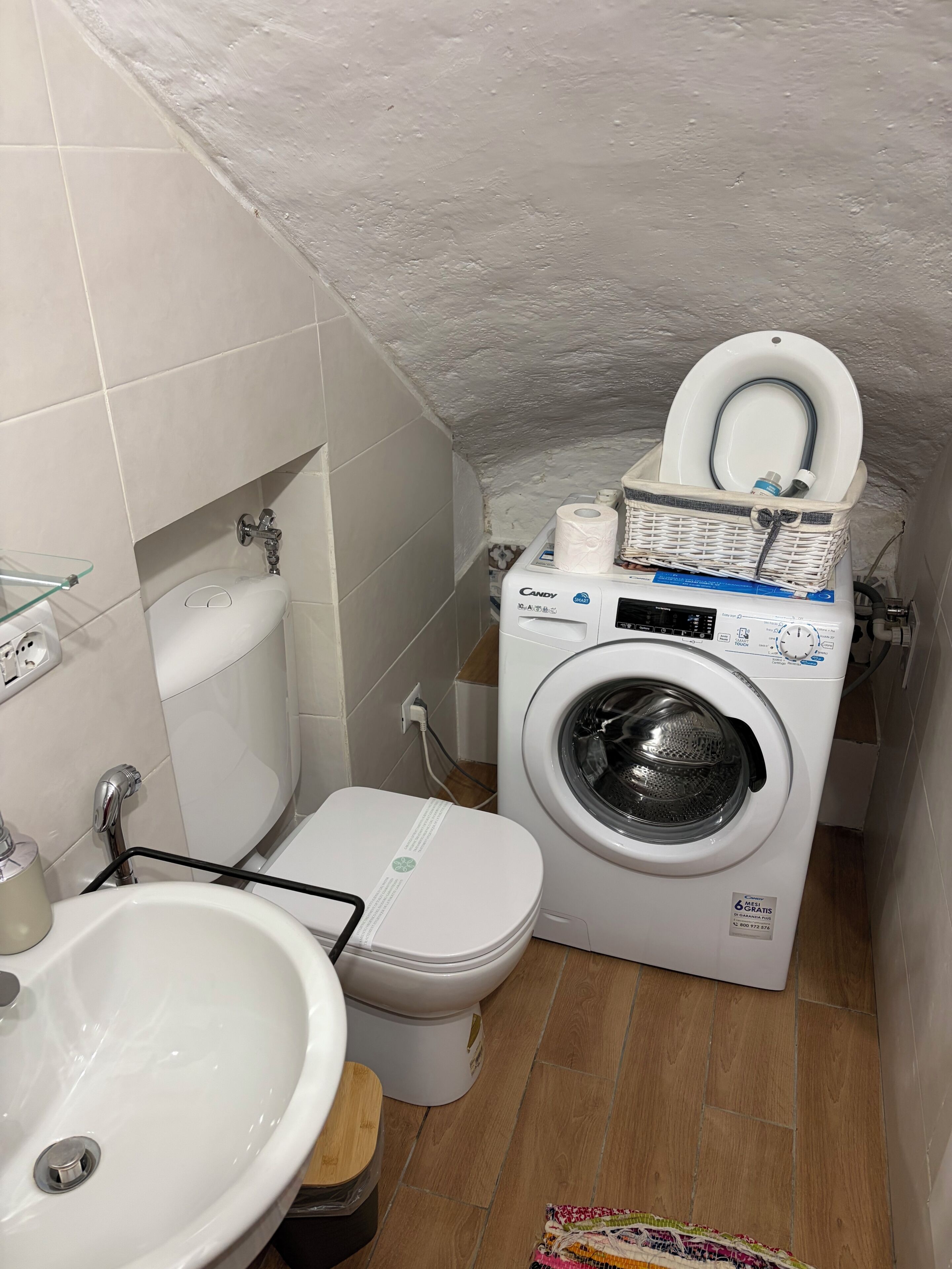 Une petite salle de bain comprenant des toilettes, un lave-linge et un lavabo.