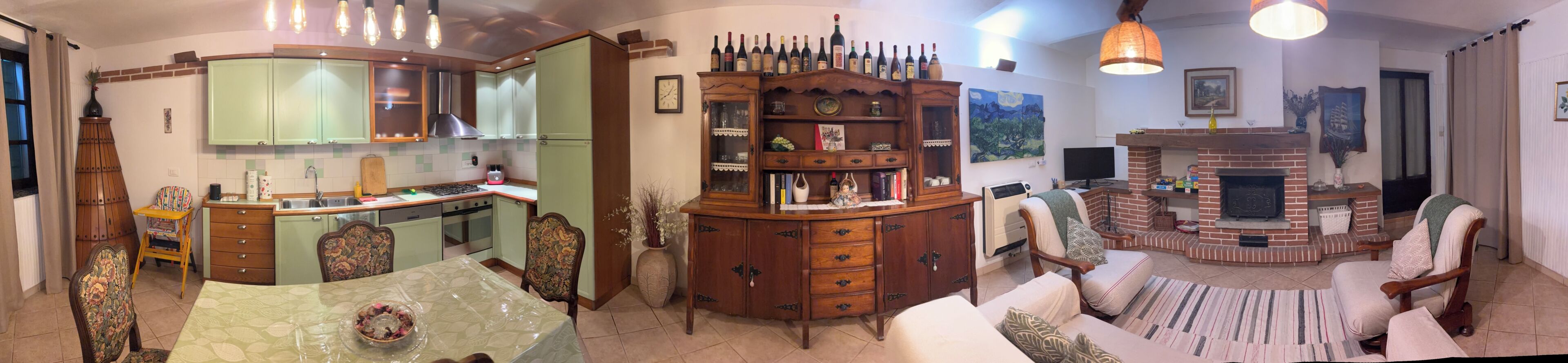 Une cuisine avec un coin repas, une cheminée et une collection de bouteilles de vin.