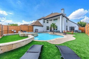 A backyard with a swimming pool, two lounge chairs, a hot tub, and a wooden deck. - Luxurious Pool Oasis  PS5 
5BR 4 BA Aquarium (Richardson)