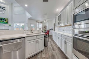A modern kitchen with white cabinetry, a built-in oven, and a dishwasher. - Luxurious Pool Oasis  PS5 
5BR 4 BA Aquarium (Richardson)
