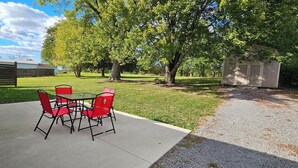 A patio with a table and chairs, a gravel path, and a garage.