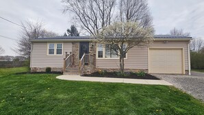 A single-story house with a front entrance, a garage, and a small tree in the front yard.