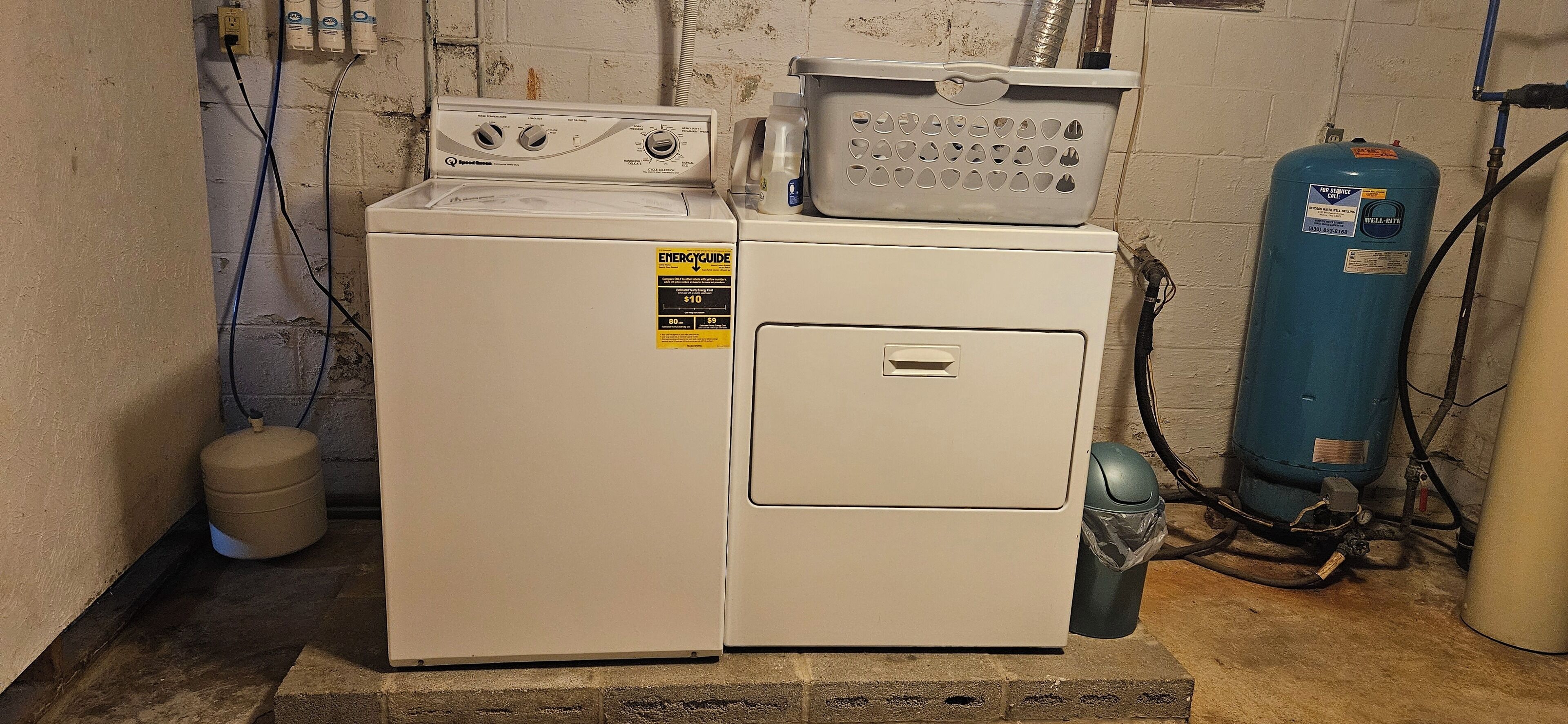 A compact washer and dryer unit with a water heater and a gas tank in a utility room.