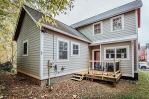Une maison à deux étages avec un porche à l’avant et une petite terrasse.