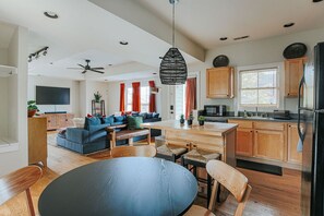Une cuisine moderne avec des meubles en bois, un réfrigérateur noir et un coin repas comprenant une table ronde et des chaises.