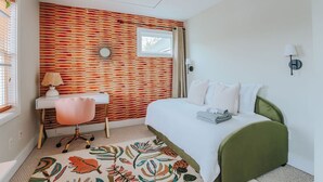 A bedroom with a bed, a desk, a chair, a window, and a wall with a striped pattern. - Oasis on 5th: walk to downtown Cville & UVA (Charlottesville,)