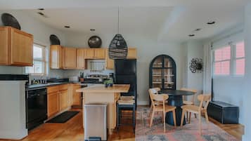A modern kitchen with wooden cabinets, a central island, and a dining area with chairs.