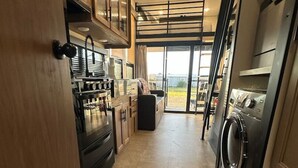 A compact kitchen with a built-in oven, microwave, and a washing machine. - Buffalo Drift Tiny Home (Interior)