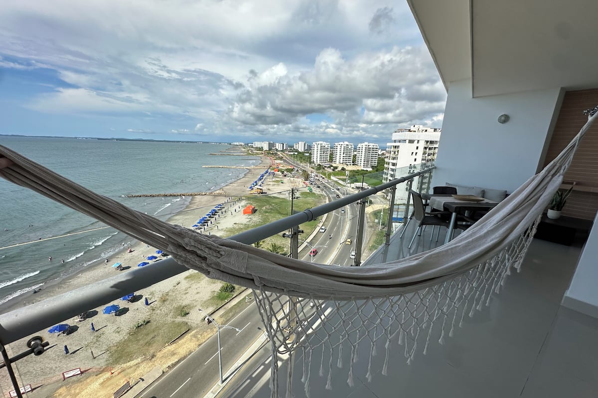 A balcony with a view of a beach, road, and buildings.
