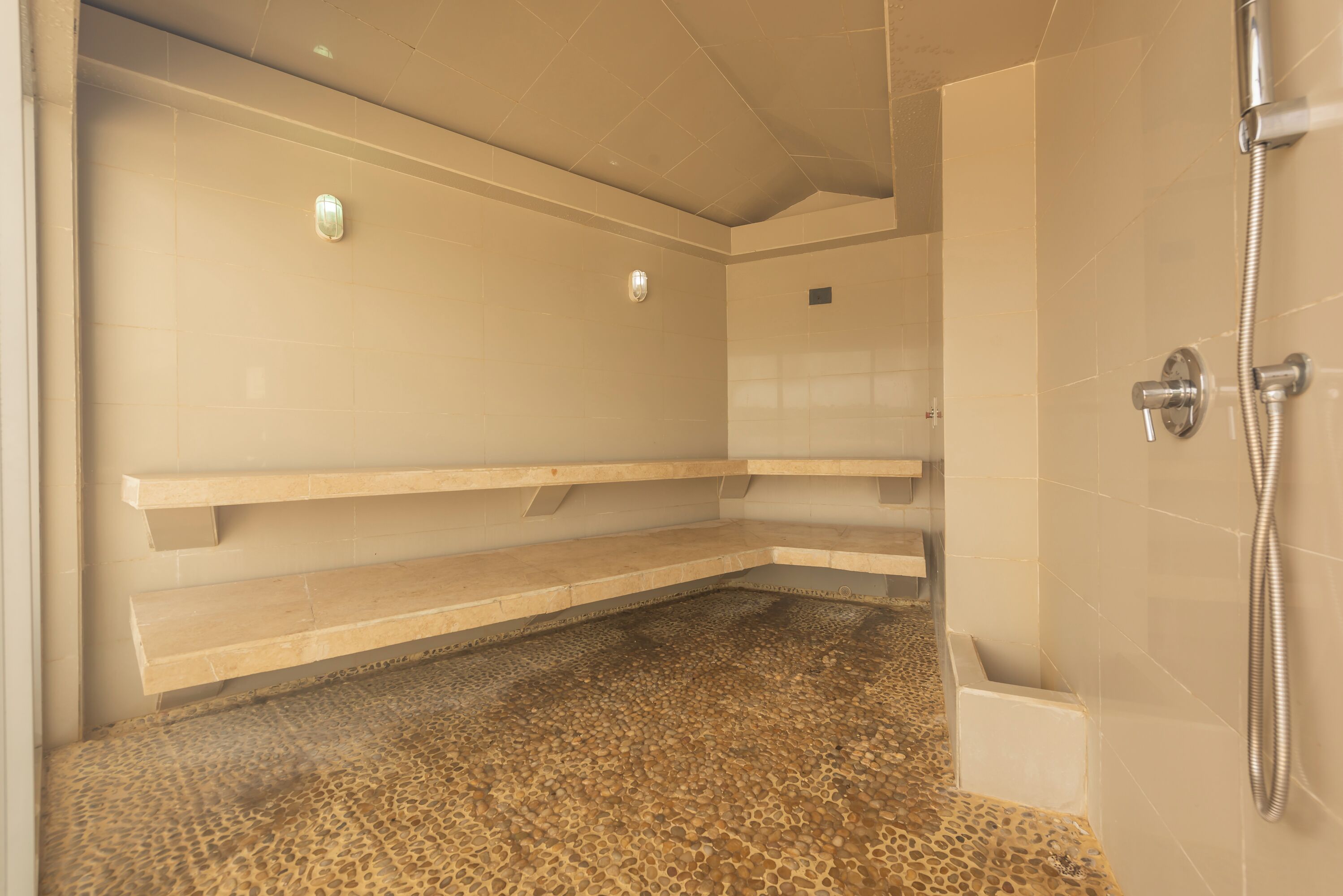 A spa room with a pebble-patterned floor, beige walls, and a shower area.