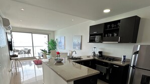 A modern kitchen with a central island, stainless steel appliances, and a dining area with a view. - Alta Mar - Bella Cartagena Apartments (Cartagena)
