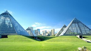 Een moderne architecturale constructie met een uniek, driehoekig ontwerp, omgeven door een verzorgd gazon.