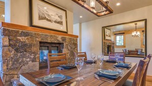 A dining area with a stone fireplace, wooden table, and chairs. - Beautiful 3 BDR Telluride Escape Close to Skiing with Private Hot Tub (Mountain Village)
