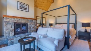 A four-poster bed, a stone fireplace, a small table with a book, and a nightstand with a lamp. - Beautiful 3 BDR Telluride Escape Close to Skiing with Private Hot Tub (Mountain Village)