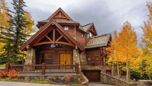 A log cabin with a stone foundation, a wooden porch, and a garage. - Beautiful 3 BDR Telluride Escape Close to Skiing with Private Hot Tub (Mountain Village)
