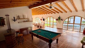 A spacious room with a pool table, wooden beams, and large windows offering a view. - Finca for events (family reunions, birthdays, weddings, seminars...) (Elda)