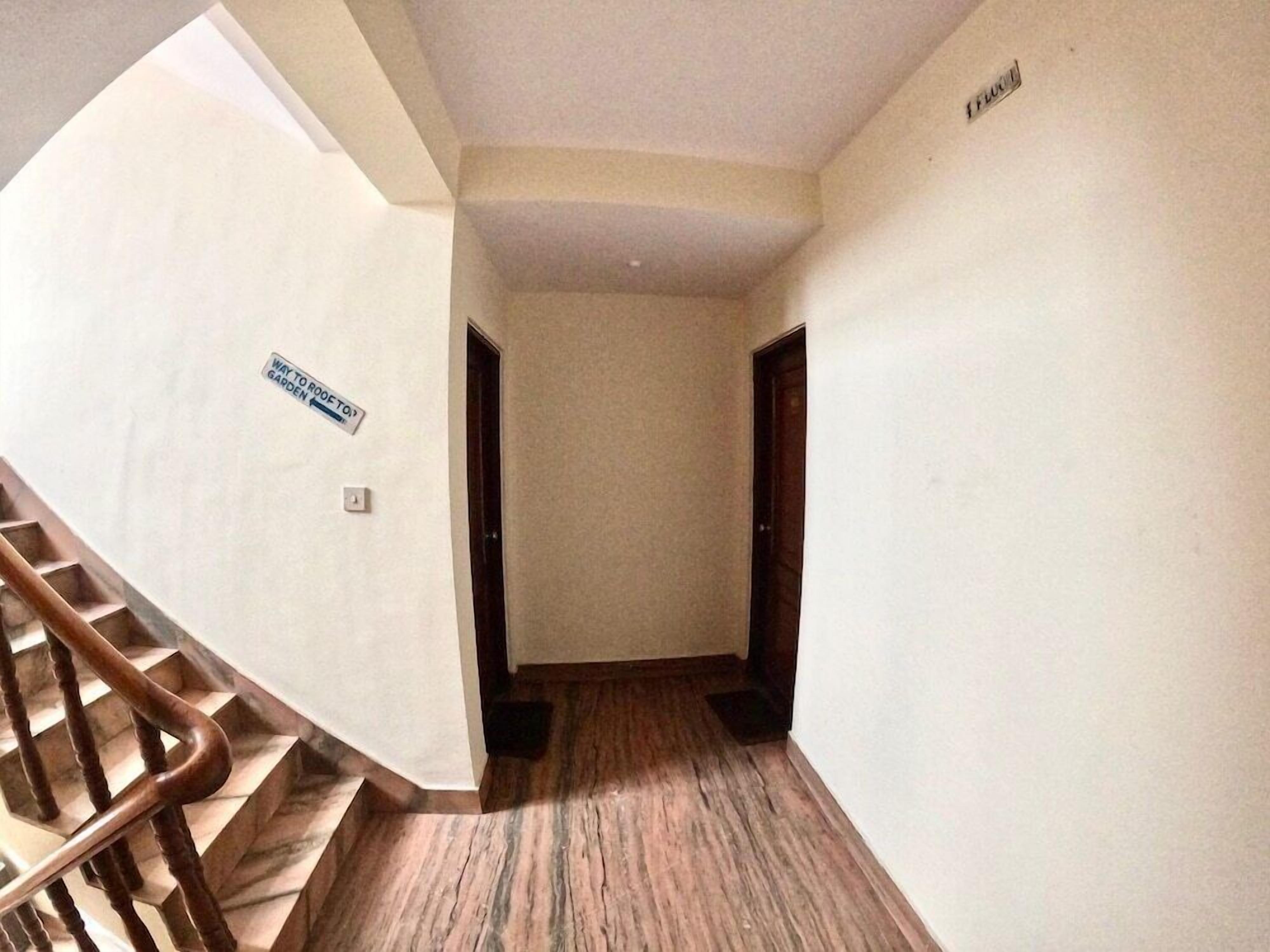 A hallway with a wooden staircase, a sign indicating a way to the garden, and a door labeled "FLOOR".