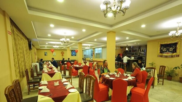 A spacious dining area with multiple tables and chairs, well-lit with ceiling lights and chandeliers. - Hotel Ghangri (Kathmandu)