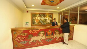 A reception desk with a traditional mural, a ceiling with a circular design, and a window with a view. - Hotel Ghangri (Kathmandu)