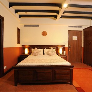 A bedroom with a wooden bed, two bedside lamps, a wooden wardrobe, and a wall-mounted light fixture. - Traditional Comfort (Kathmandu)