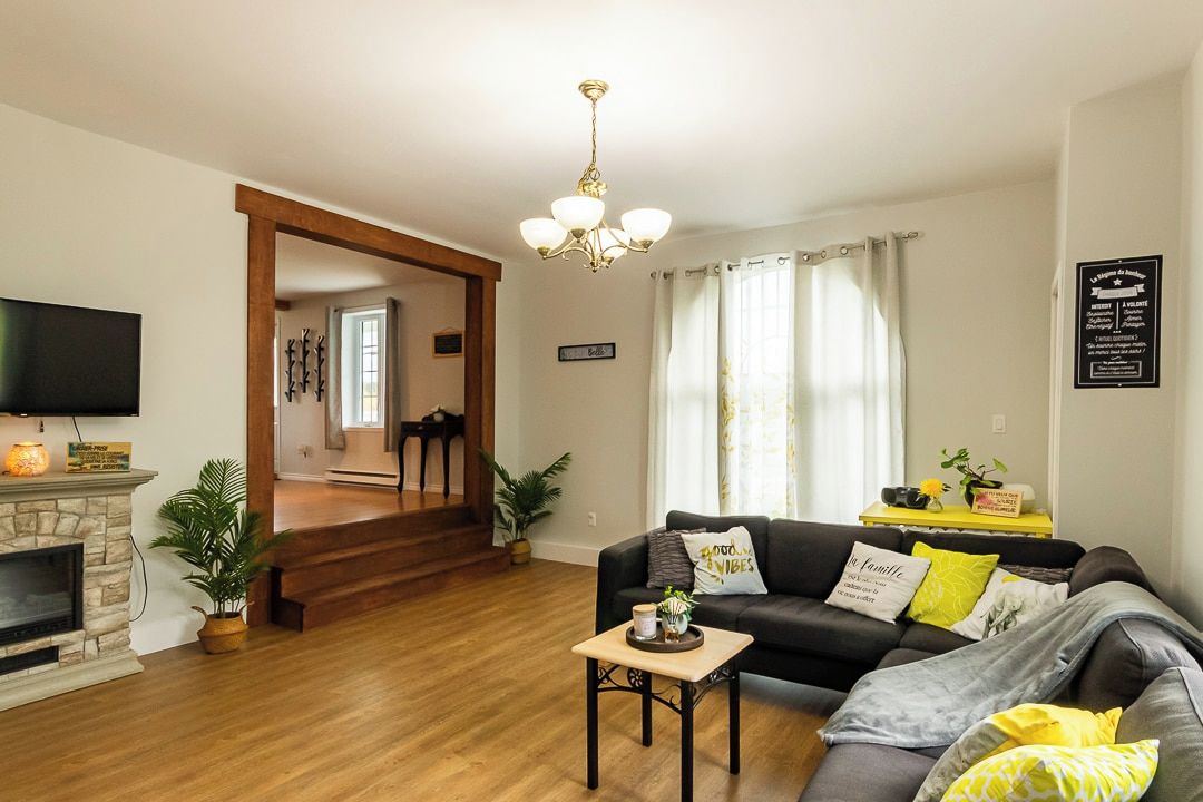Uma sala de estar com lareira, sofá, mesa de centro e televisão.