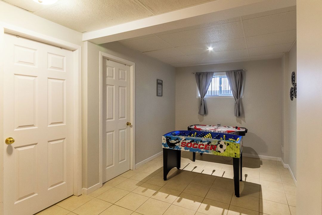 Un couloir avec une table de baby-foot, une porte et une fenêtre avec des rideaux.