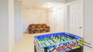 Una habitación con mesa de futbolín, un sofá estampado y puertas blancas.