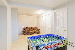 A room with a foosball table, a patterned sofa, and white doors.
