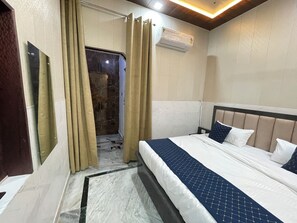 A hotel room with a bed, curtains, a mirror, and an air conditioning unit. - Taran Bliss homestay Agra  (Agra)