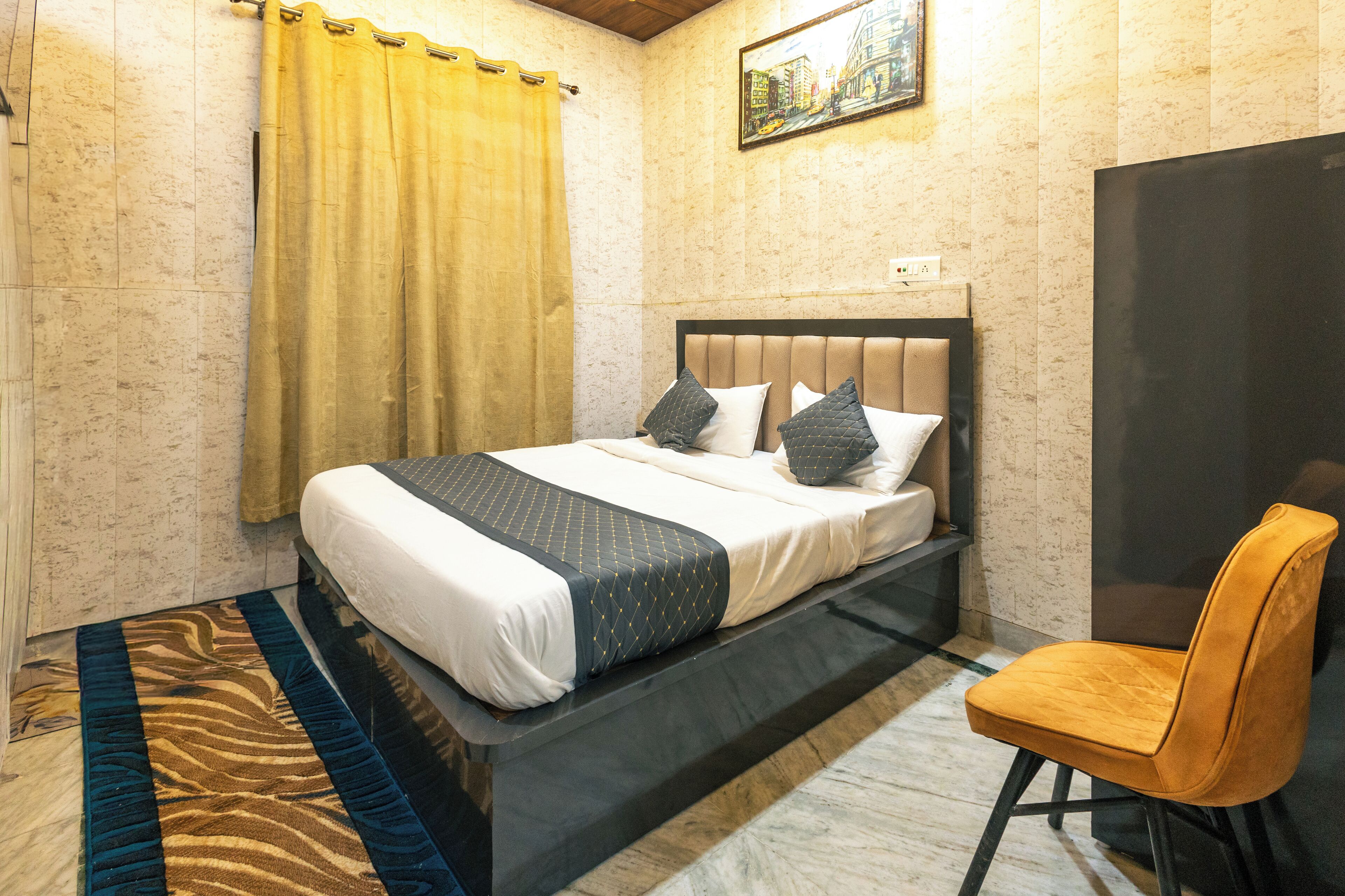 A hotel room with a bed, a chair, a zebra-patterned rug, and a painting on the wall.