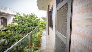 Um edifício moderno com varanda, plantas em vasos e vista para o verde.