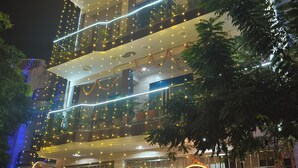 Um edifício de vários andares com varandas decoradas com luzes de cordão e um letreiro para 'Taran Bliss Homes Stay'.