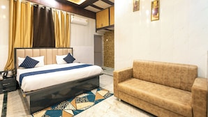 Quarto moderno com cama, sofá, tapete estampado e ventilador de teto.