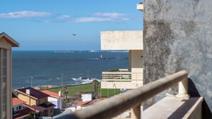 A coastal view with a building, a pier, and a ship in the distance.