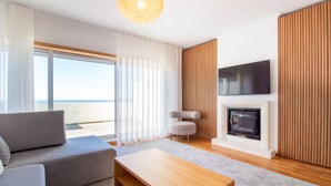 A modern living room with a sofa, a coffee table, a fireplace, and a TV mounted on the wall.
