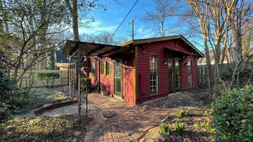 A red wooden house with a brick pathway leading to the entrance.