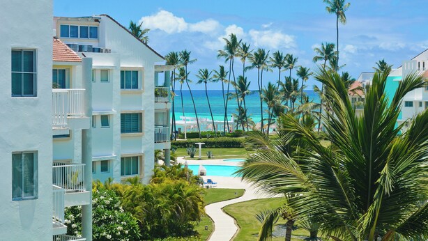 Ein Resort mit Pool, Palmen und Blick auf den Ozean.