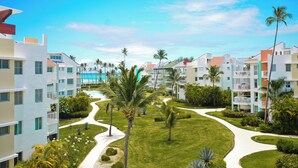 Ein Resort mit mehrstöckigen Gebäuden, einem zentralen Weg und Palmen.