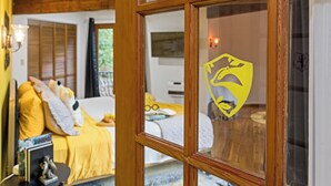 Een kamer met een bed, een nachtkastje en een raam met een geel symbool.