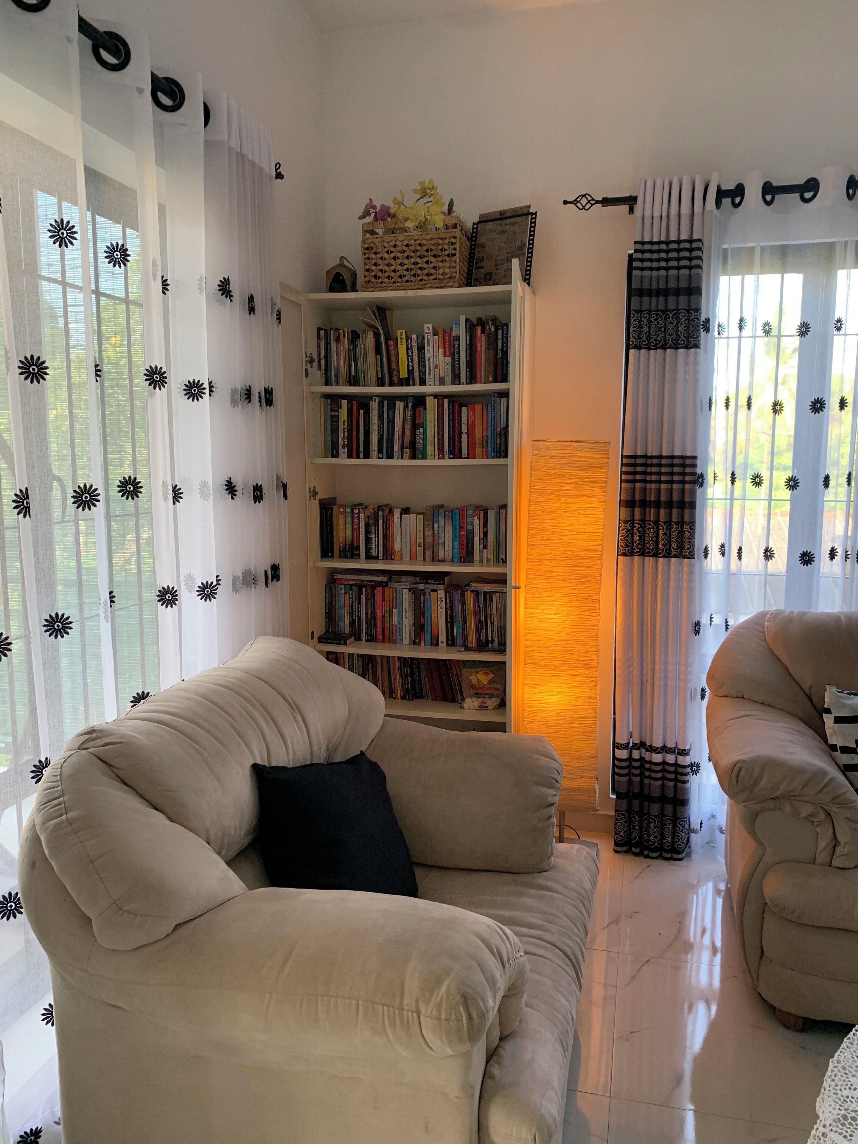 Un salon chaleureux avec un canapé beige, une bibliothèque remplie de livres et une décoration murale.