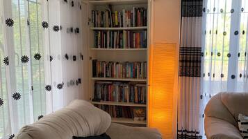 Un salon chaleureux avec un canapé beige, une bibliothèque remplie de livres et une décoration murale.