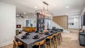 A modern kitchen with a central island, wooden chairs, and a dining table set for six. - Western Boots & Spa-Hot Tub, BBQ, Firepit, Gameroom & Good Times! (Houston)