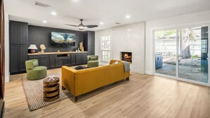 A modern living room with a sofa, a fireplace, and a television. - Western Boots & Spa-Hot Tub, BBQ, Firepit, Gameroom & Good Times! (Houston)