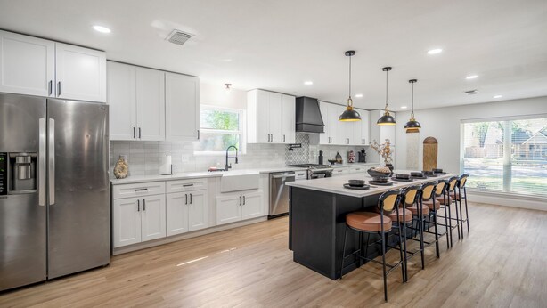 A modern kitchen with white cabinets, stainless steel appliances, and a central island with bar stools. - Western Boots & Spa-Hot Tub, BBQ, Firepit, Gameroom & Good Times! (Houston)