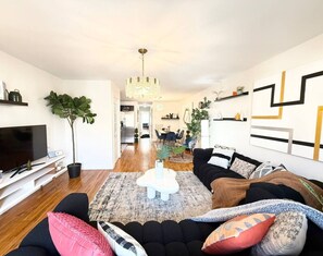 Een moderne woonkamer met een bank, televisie en sierplanten.