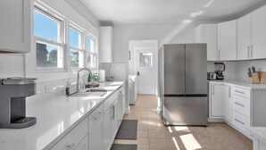 Eine moderne Küche mit weißen Schränken, einem Edelstahl-Kühlschrank und einer Kaffeemaschine.