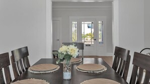 Ein Esszimmer mit einem dunklen Holztisch, sechs Stühlen und einer Vase mit Blumen.