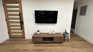 A living room with a wooden entertainment center, a flat-screen TV mounted on the wall, and a door with a wooden panel design.